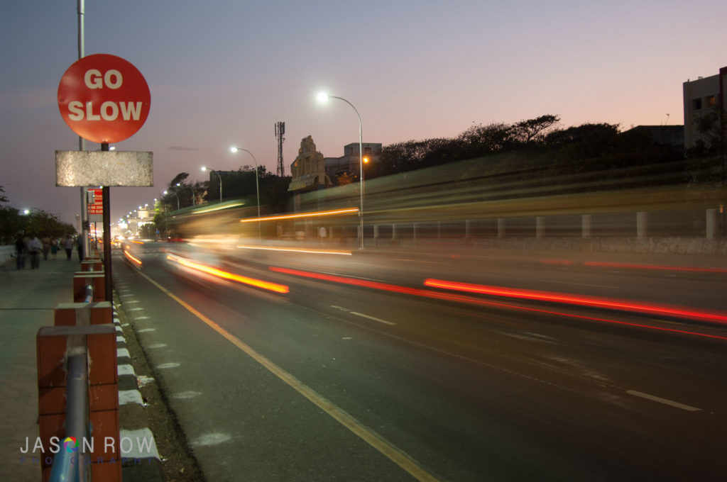 Cars speed past a go slow sign in Chennai India 