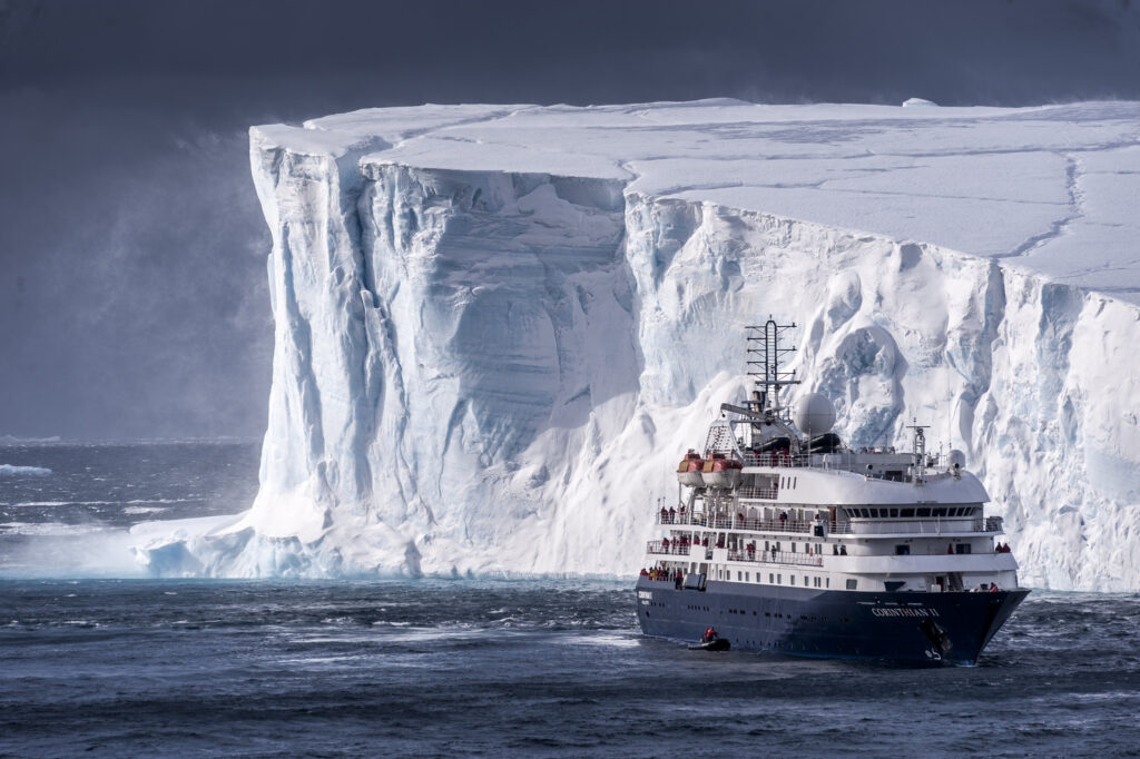 Cruise ship beside massive iceberg in Antarctica