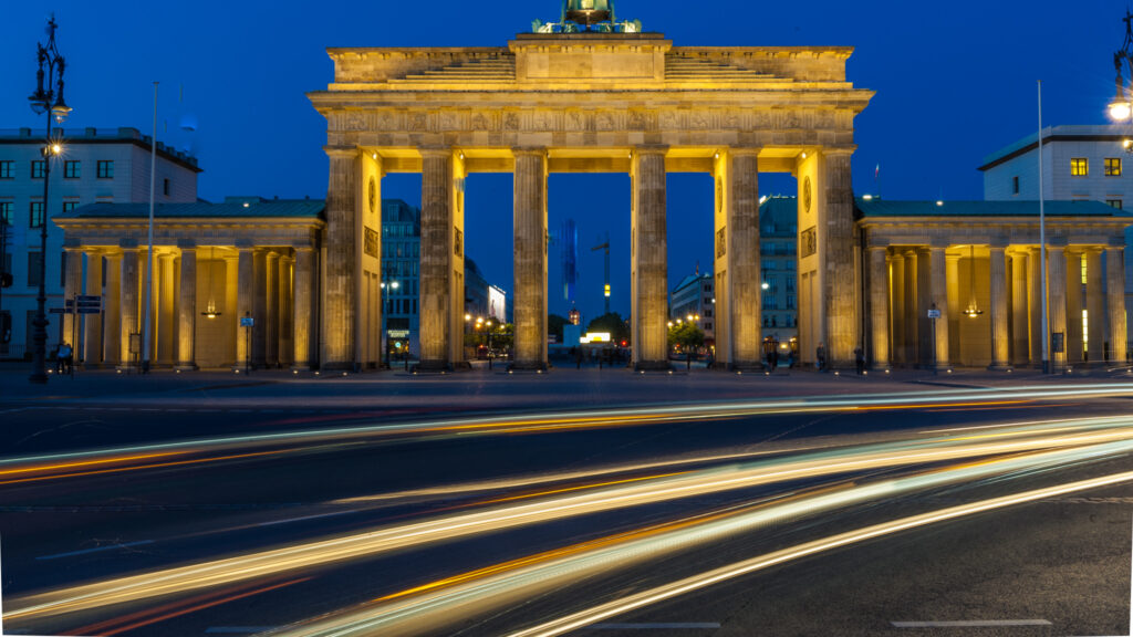 Car light trails streak in front of the Brandenburg gate in the evening. Berlin