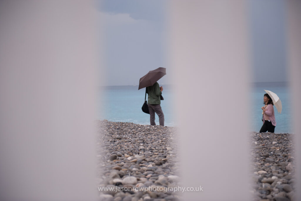 A glimpse of tourists with umbrellas on the beach in Nice, France 