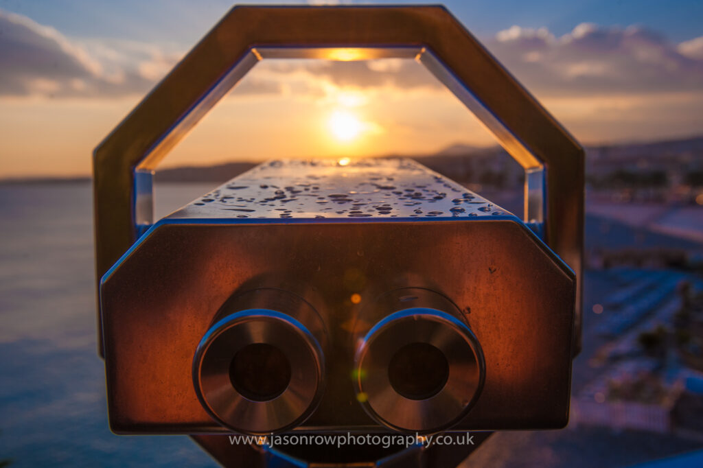 A tourist binocular looks out over Nice as the sun sets 