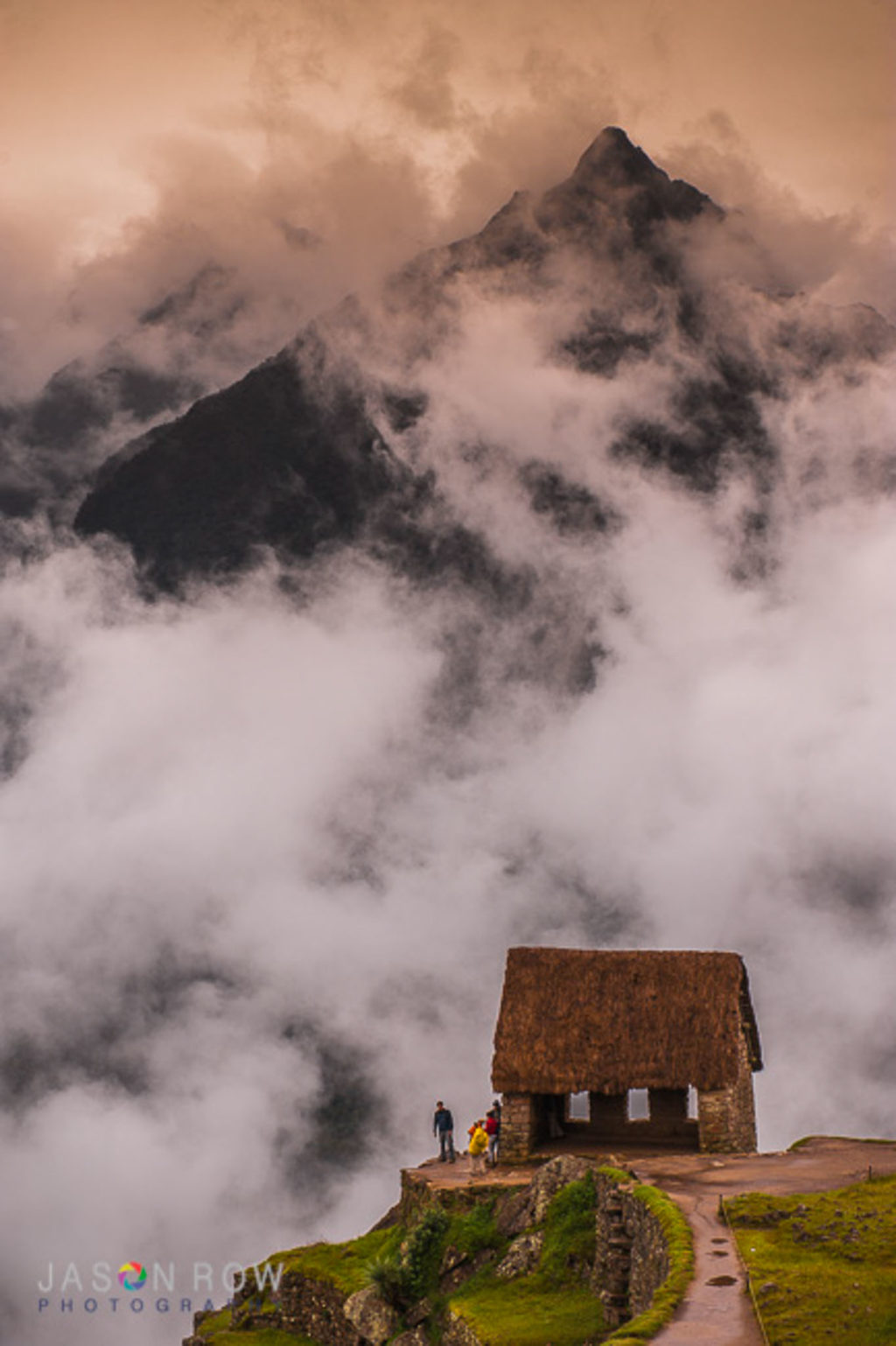 Clouds rise around and over the gatekeepers hut in Machu Picchu, Peru. The Peruvian highlands rise in the background