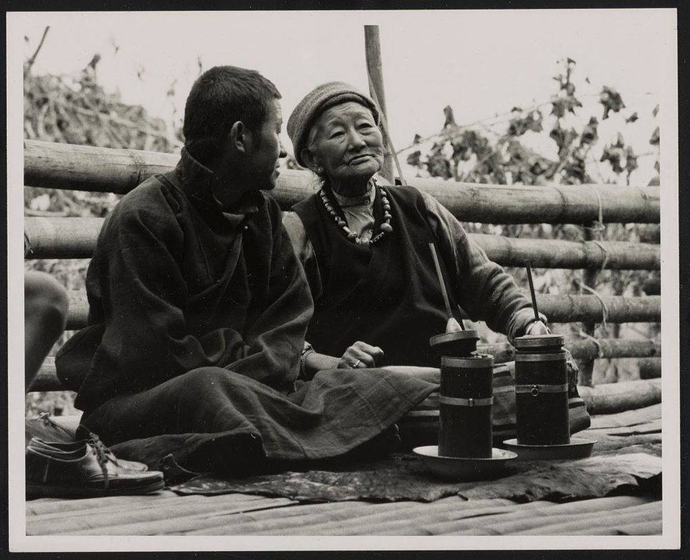 Bhutia couple drinking millet beer from a straw on their house terrace in Western Sikkim