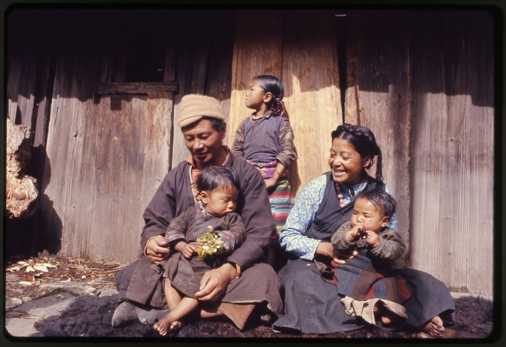 Photograph shows the mother, father and children of the Jorbu family, seated outside their home, Lachung, Sikkim