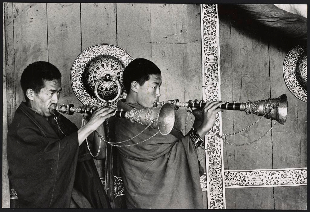 Lamas blowing gyalings at temple door