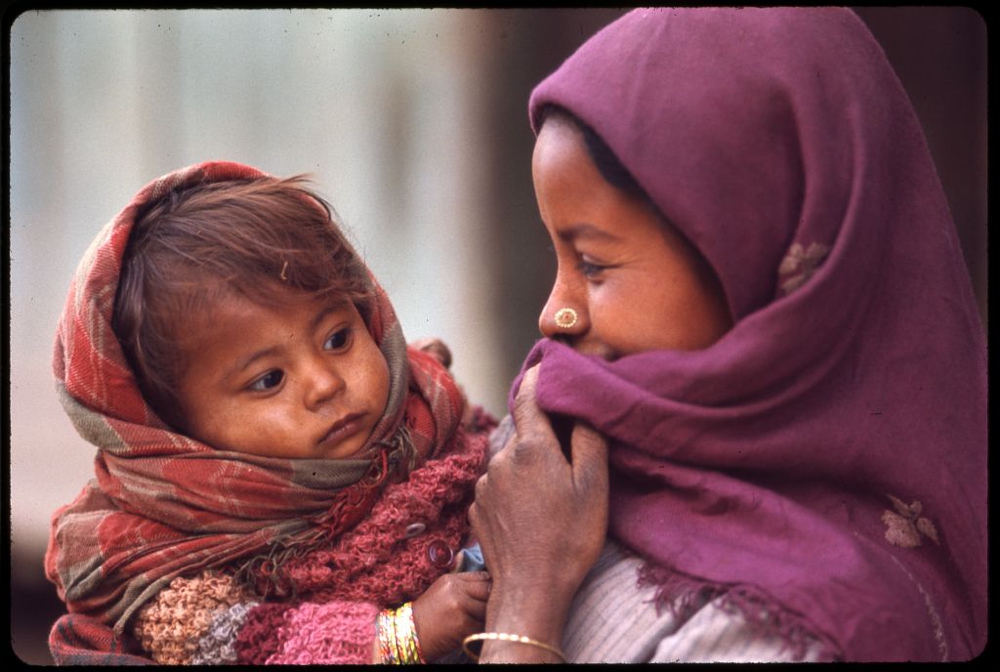 Nepalese woman wearing purple headscarf and nose ring, holding baby, Sikkim