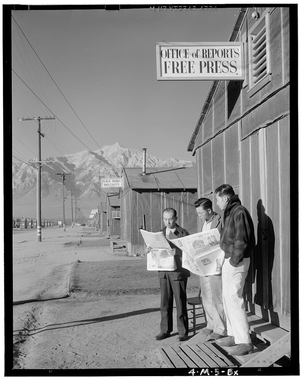  Roy Takeno (Editor) and group reading Manzanar paper [i.e. Los Angeles Times] in front of office, Yuichi Hirata, Nabuo Samamura, Manzanar Relocation Center, California