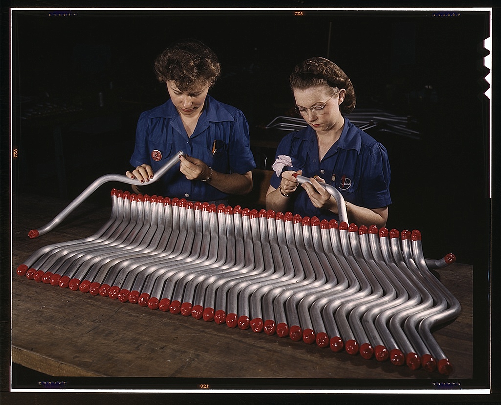 Two women workers are shown capping and inspecting tubing