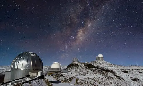 a few round objects on a rocky surface with stars in the sky