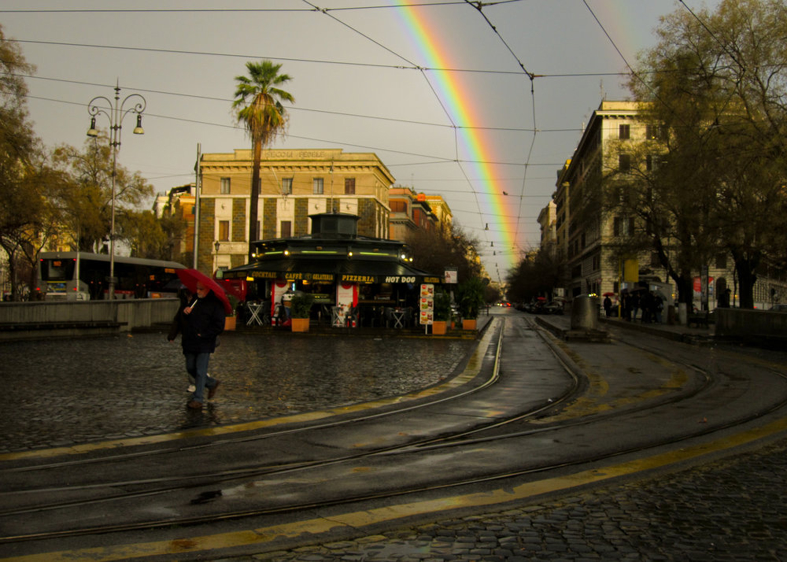 a person walking down a street with a rainbow in the background