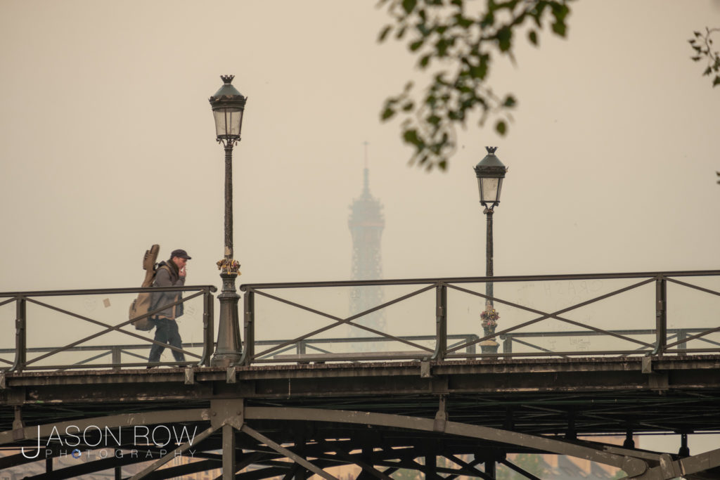 Long shot of man walking across the Pont des Art Paris towards t