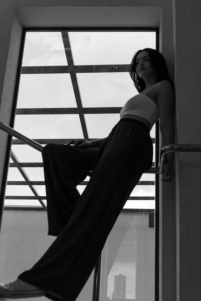 a woman leaning up against a window sill