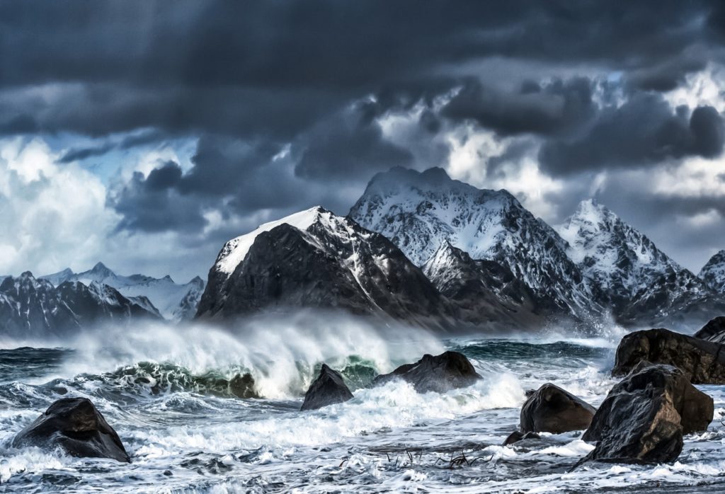 Storm over waves meeting mountains.