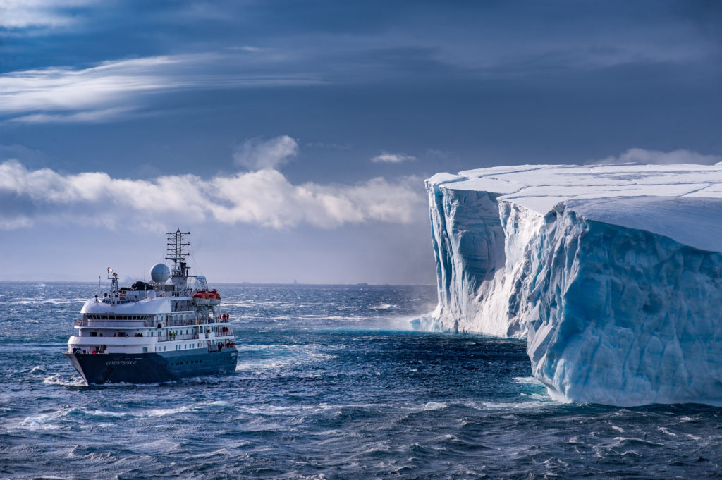 cruise ship beside massive iceberg in Antarctica