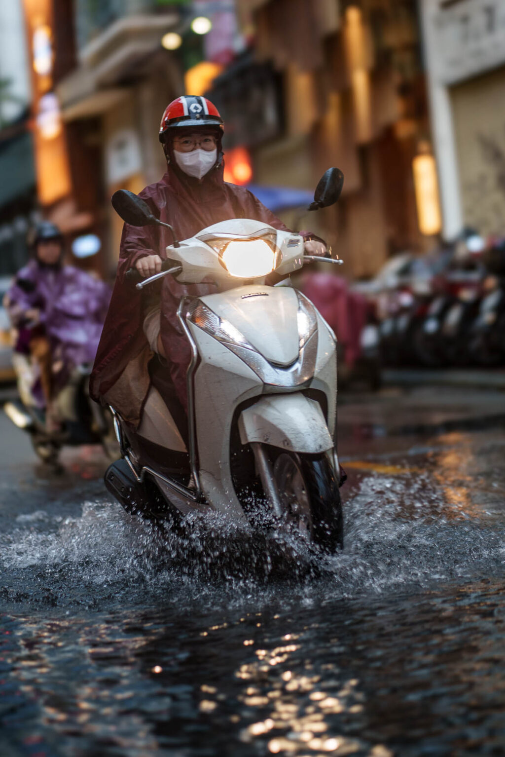 A moped rider in Vietnam speed through a flooded road