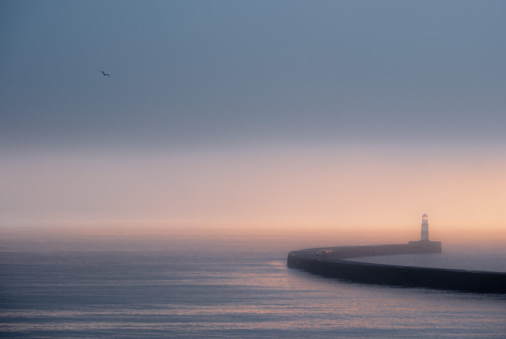 Seaham light house on a misty winter day as the sun rises