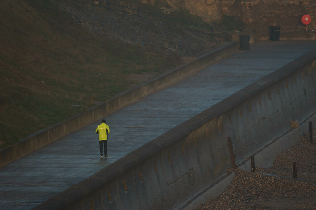 Man in yellow sports gear running along a pier