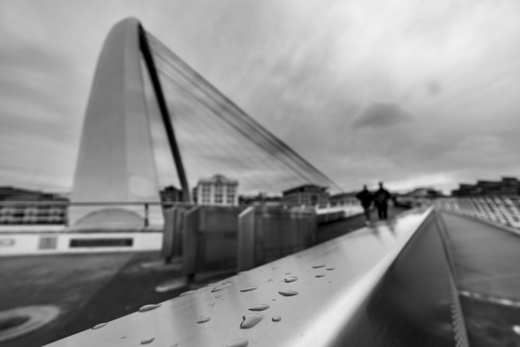 Defocussed black and white image of raindrops with the Newcastle Milennium Bridge behind 