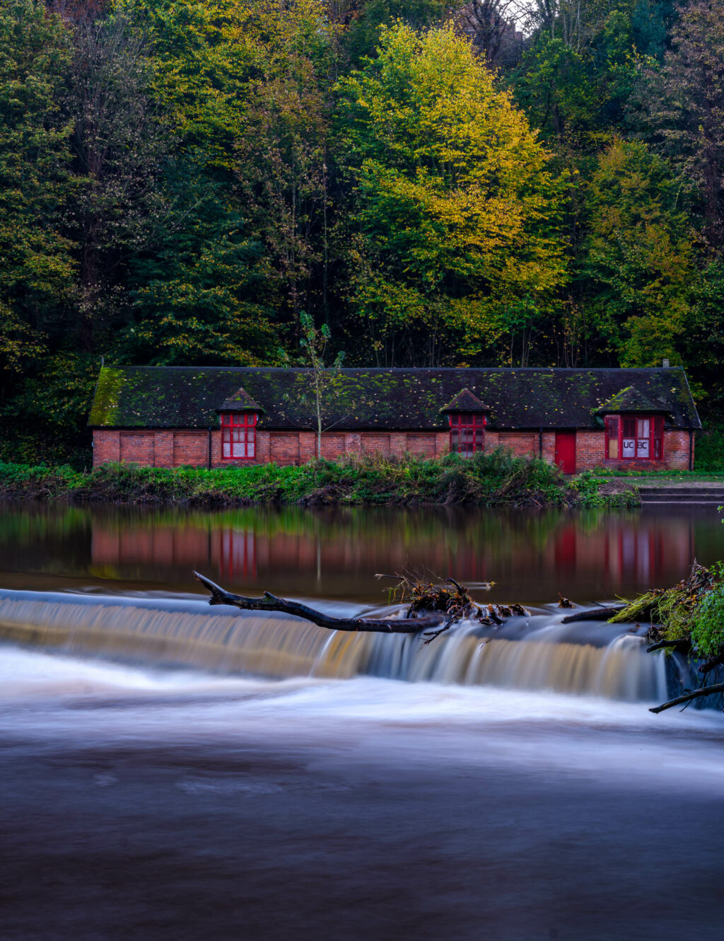 Old boathouse and weir on the River Wear at the height of autumn