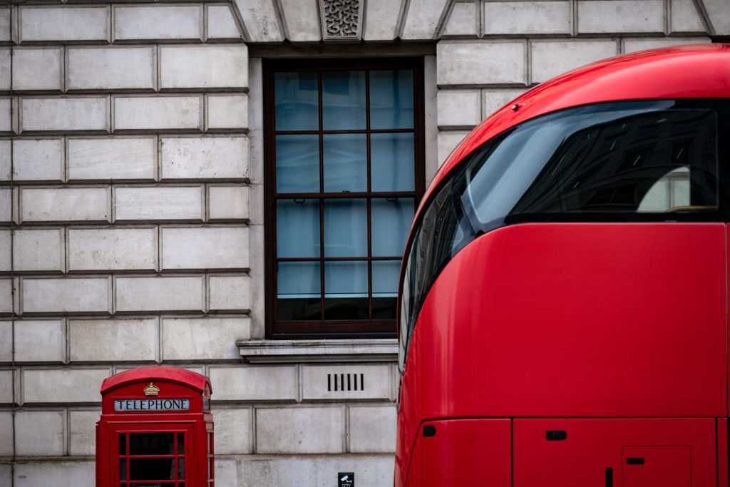 London bus and telephone box by a government building. 