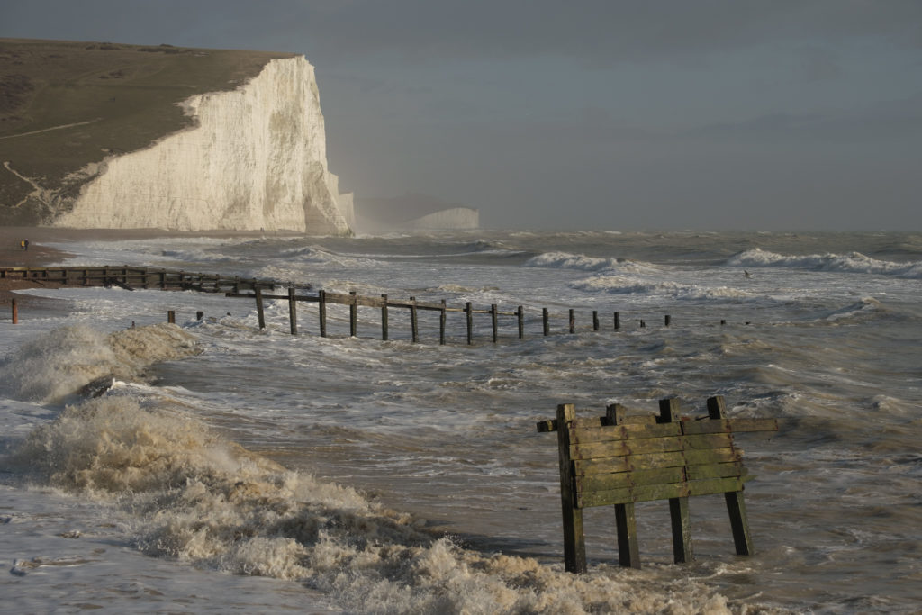 Wave crash ashore in front of Seven Sisters Cliffs in storm