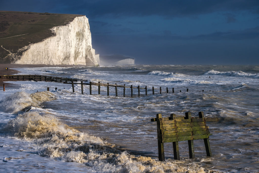Wave crash ashore in front of Seven Sisters Cliffs in storm