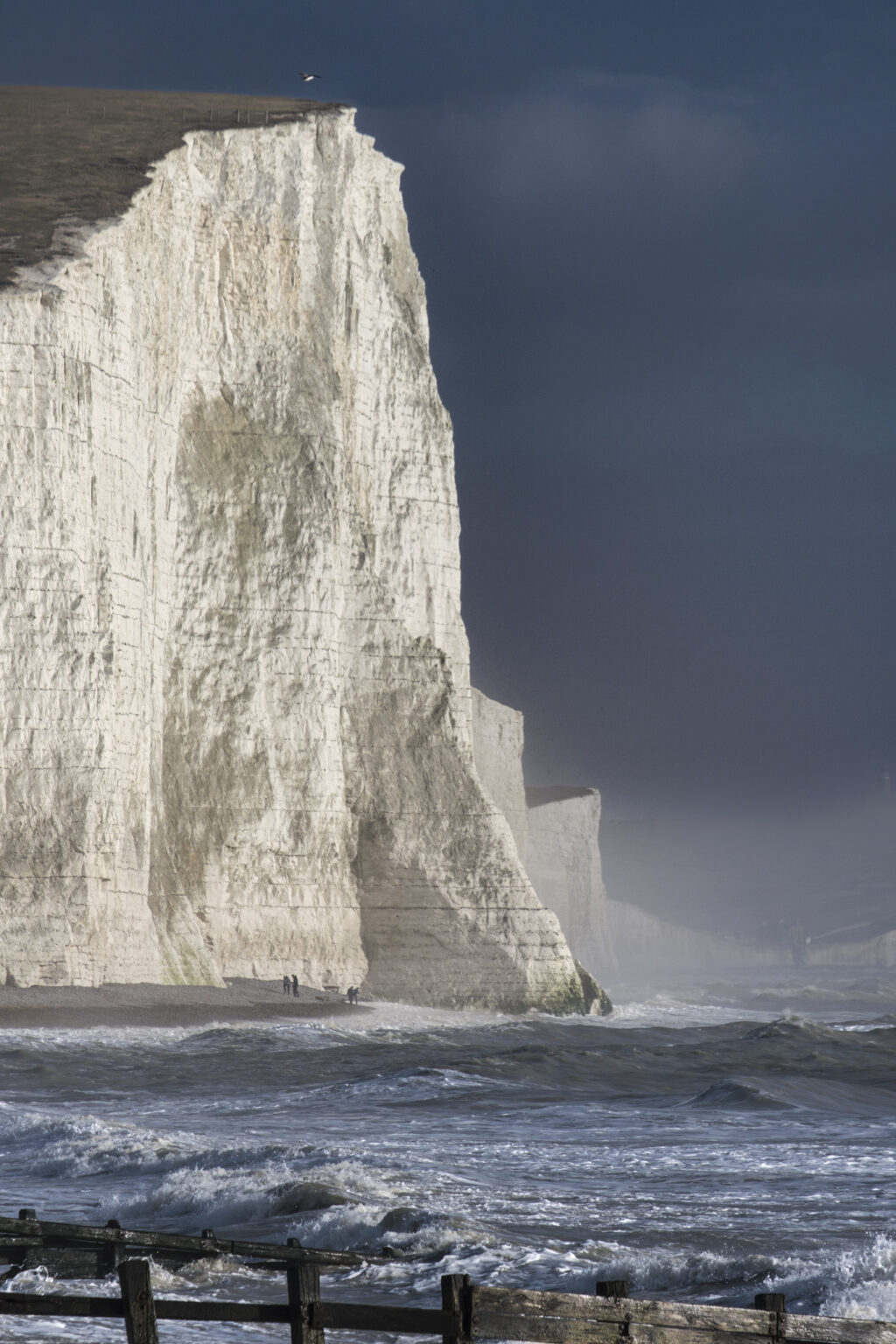 Seven Sisters Cliffs in storm with people in distance
