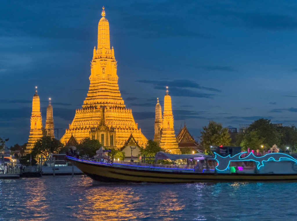 Tourist boat passes Wat Arun in Bangkok during twlight