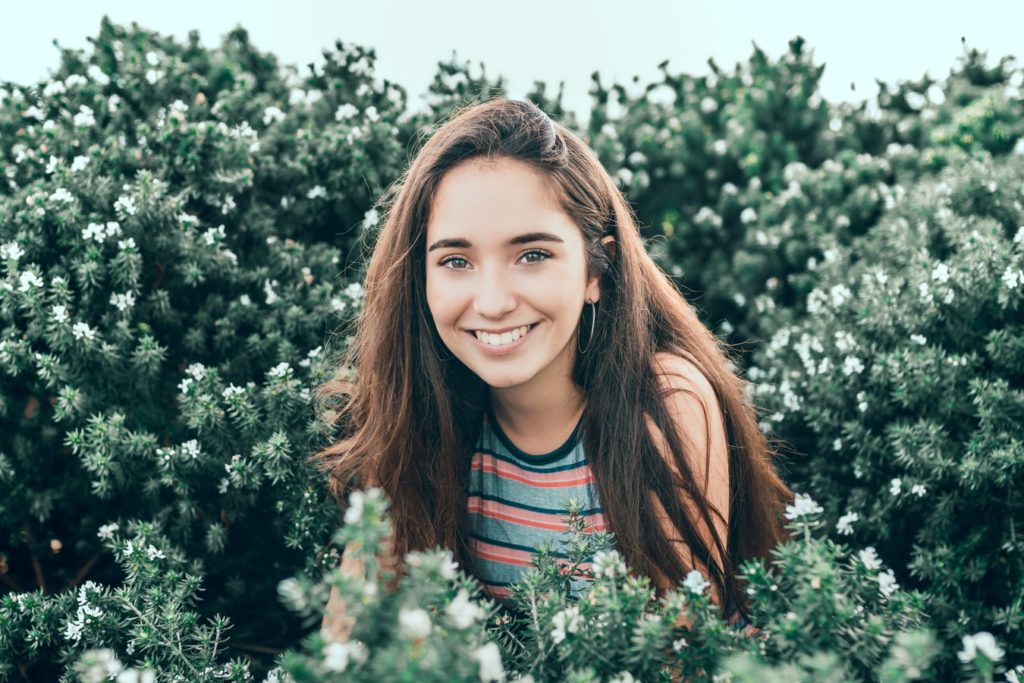 a person smiling in front of a bush