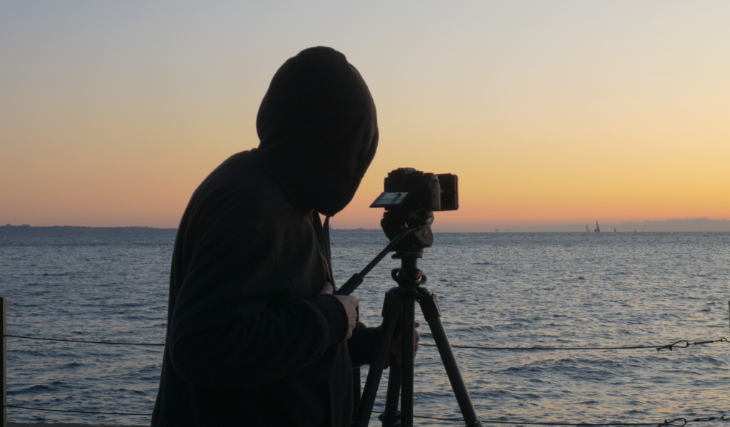 Man shooting video on coast during sunrise 