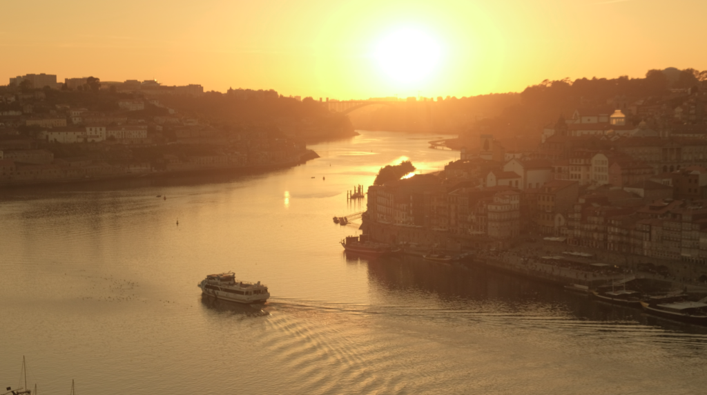 a boat sails into sunset in Porto, Portugal