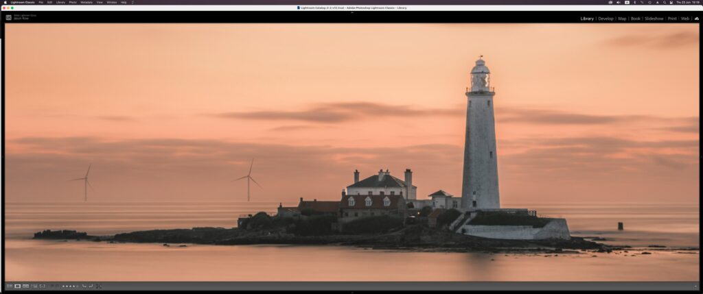 Screenshot of a lighthouse being edited in Lightroom on a widescreen monitor 