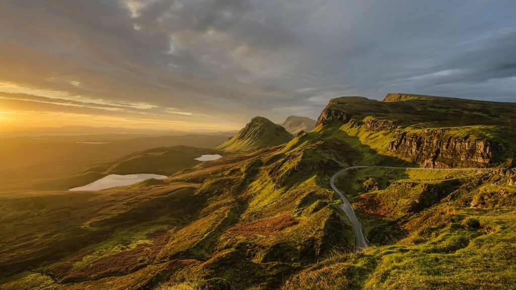 a landscape with a river running through it with Quiraing in the background