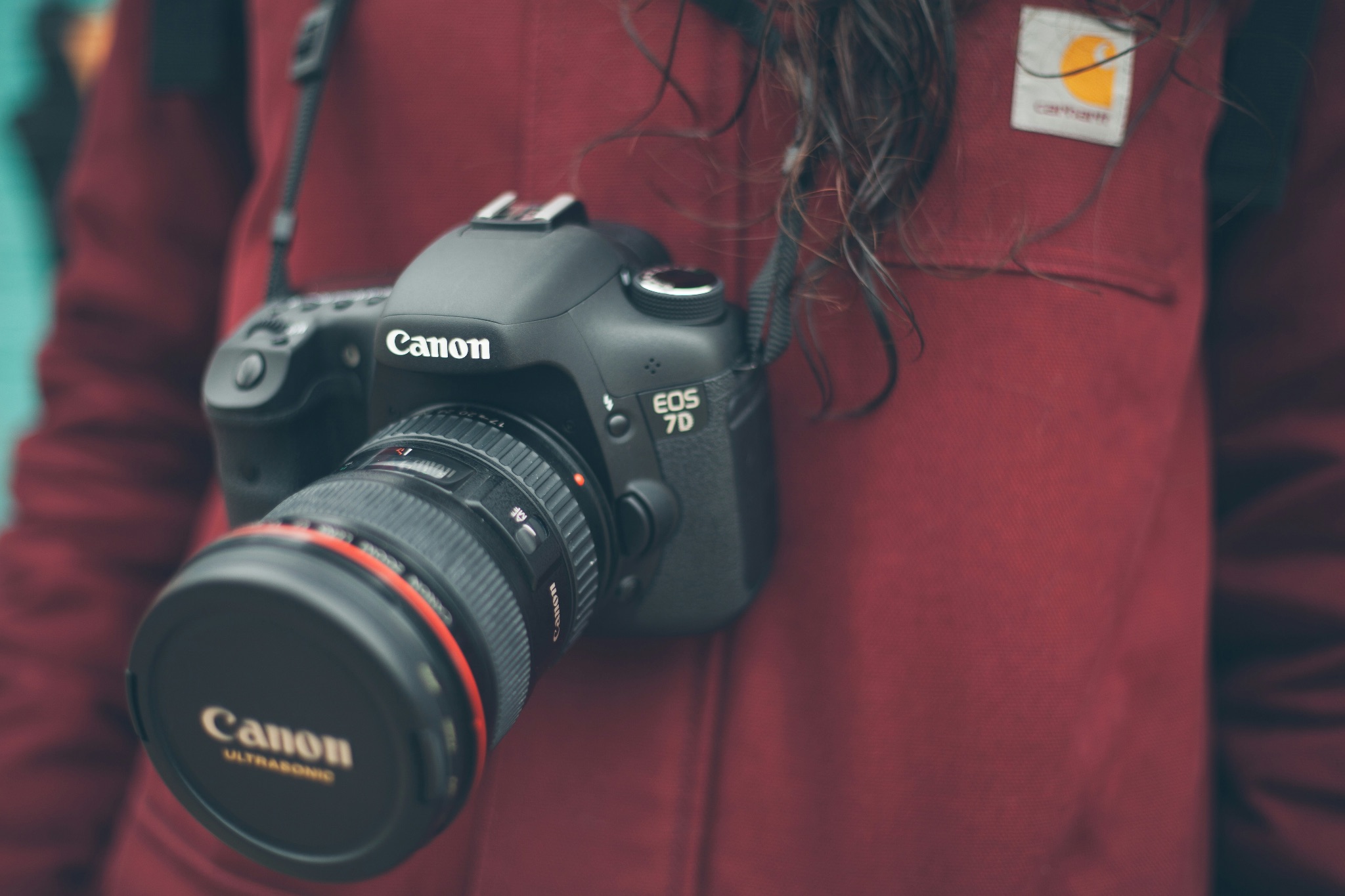 A canon 7D camera hanging on a strap from a photographer's neck