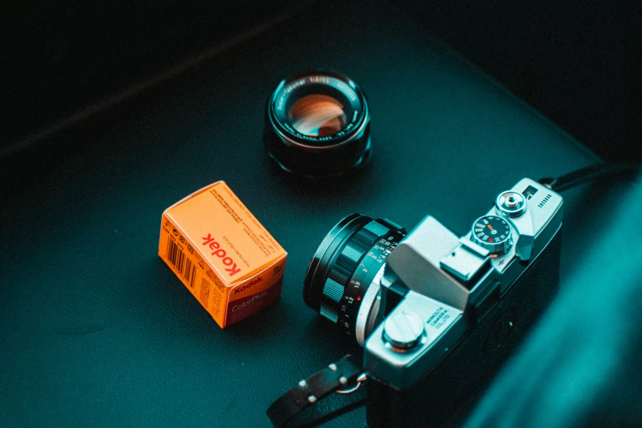 A film camera with a roll of Kodak print film beside it. 