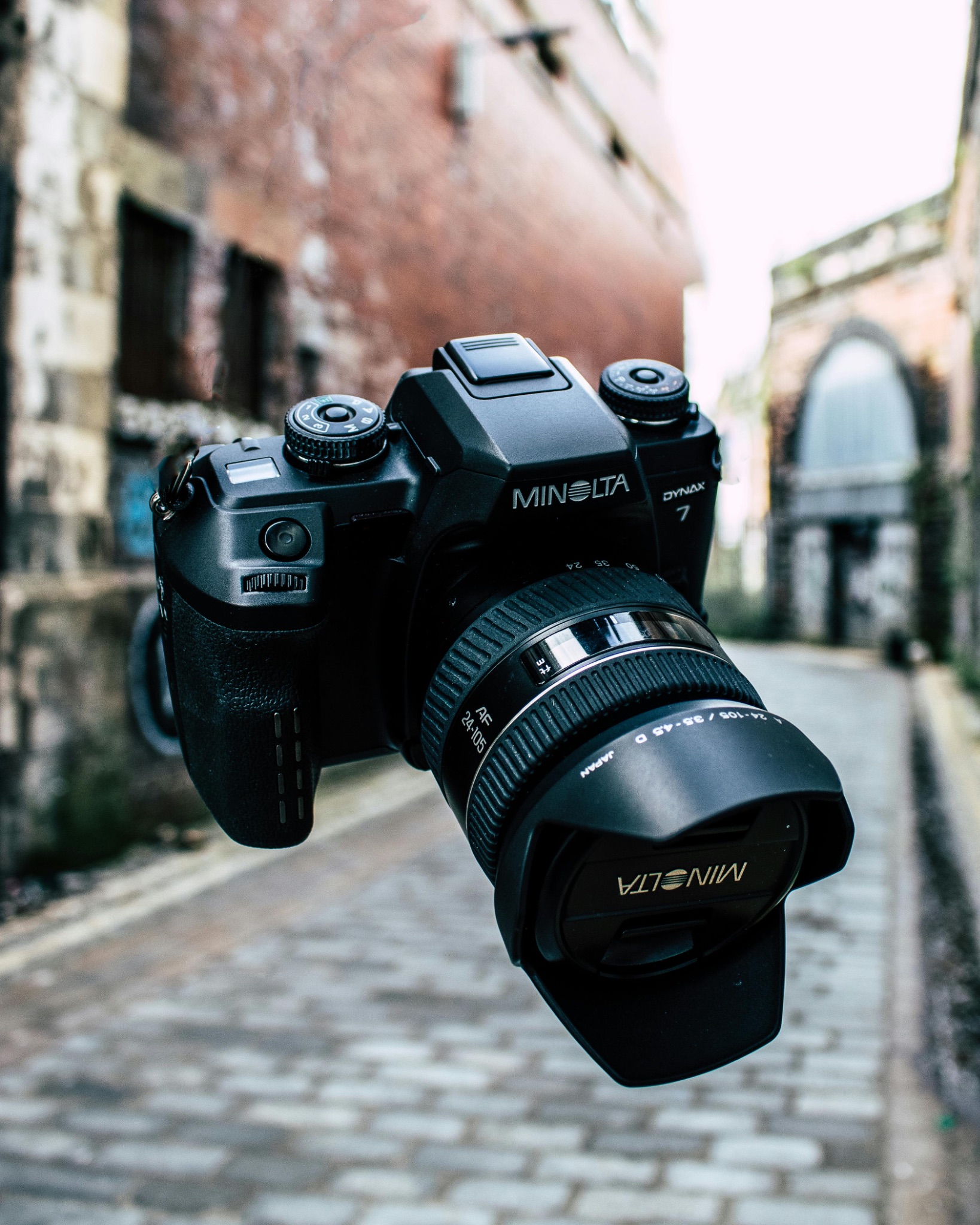 A Minolta Dynax 7 film camera seemingly hanging in mid air in a street 