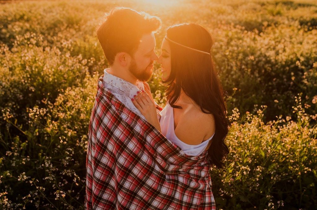 a man and woman kissing in a field of flowers