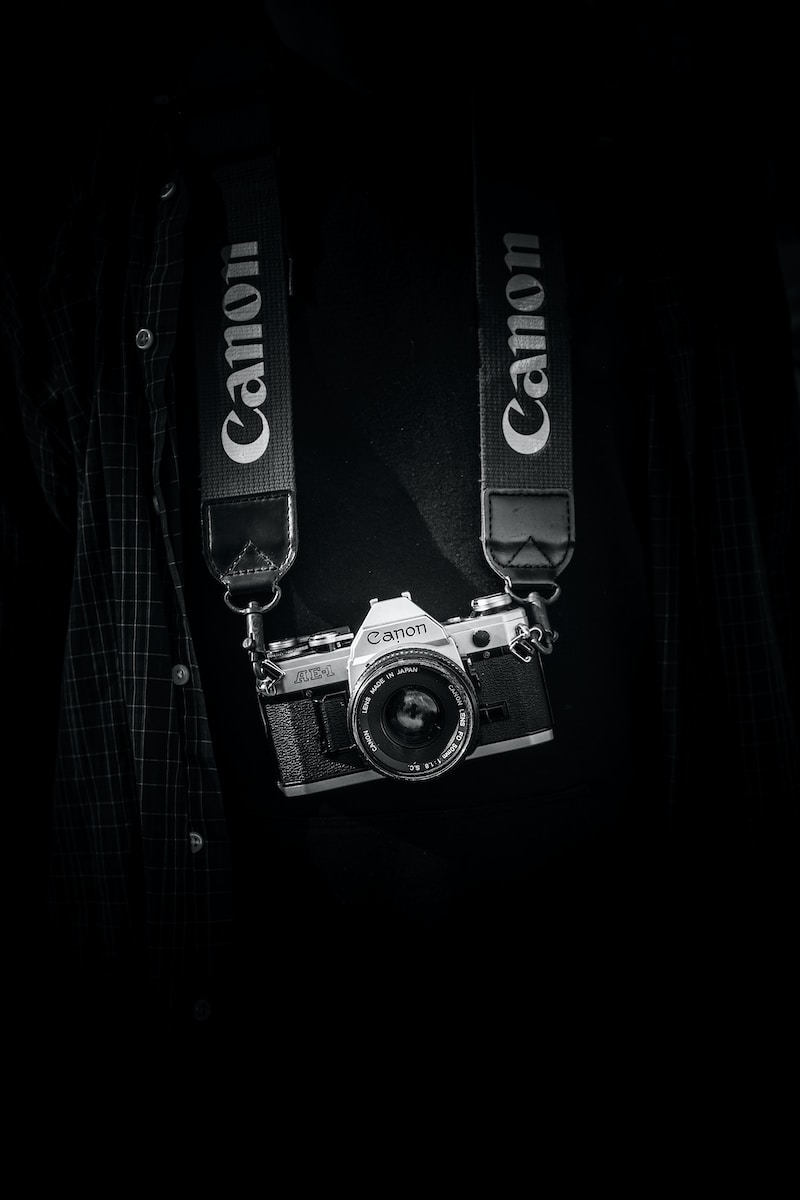 gray and black Canon camera body with lanyard