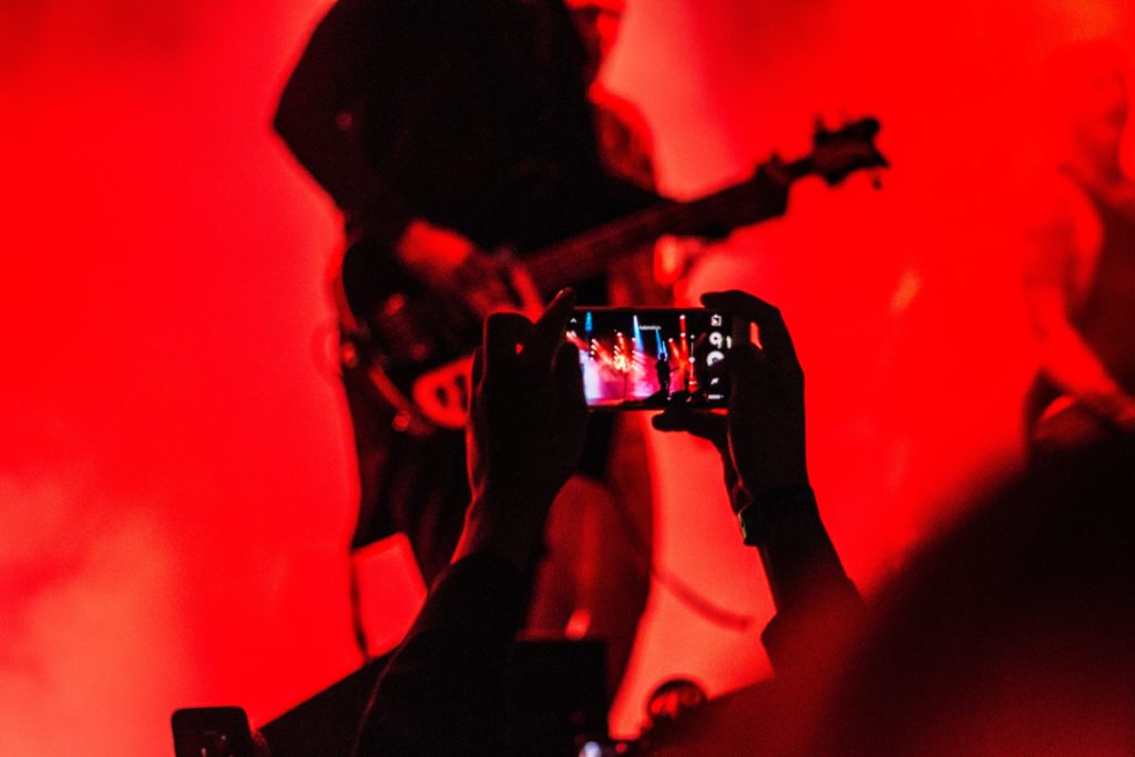 Person using camera phone taking photo of rock concert