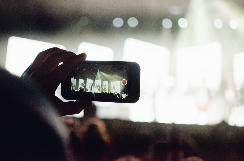 Man shooting video on phone at concert