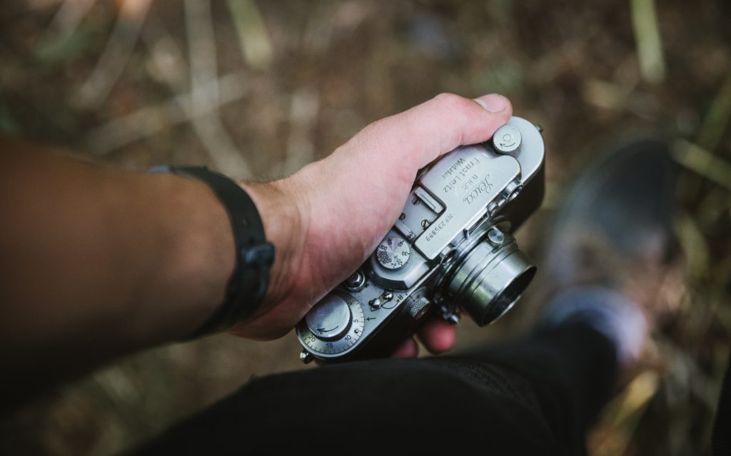 Hand holding a vintage Leica film camera. 