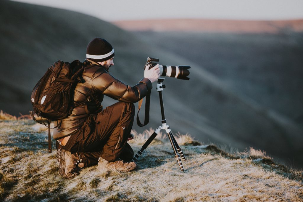 Photographer takes photo on top of a mountain 