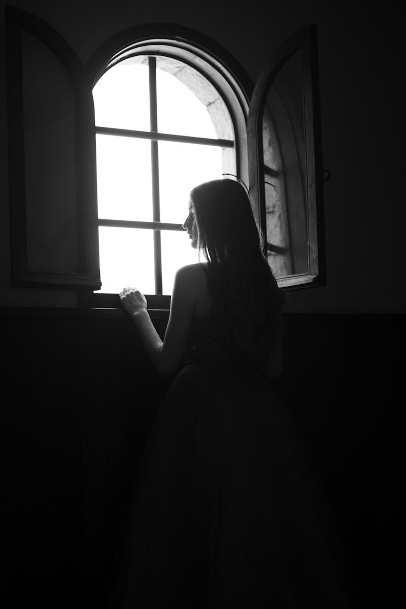 a woman looking out of a window in a dark room