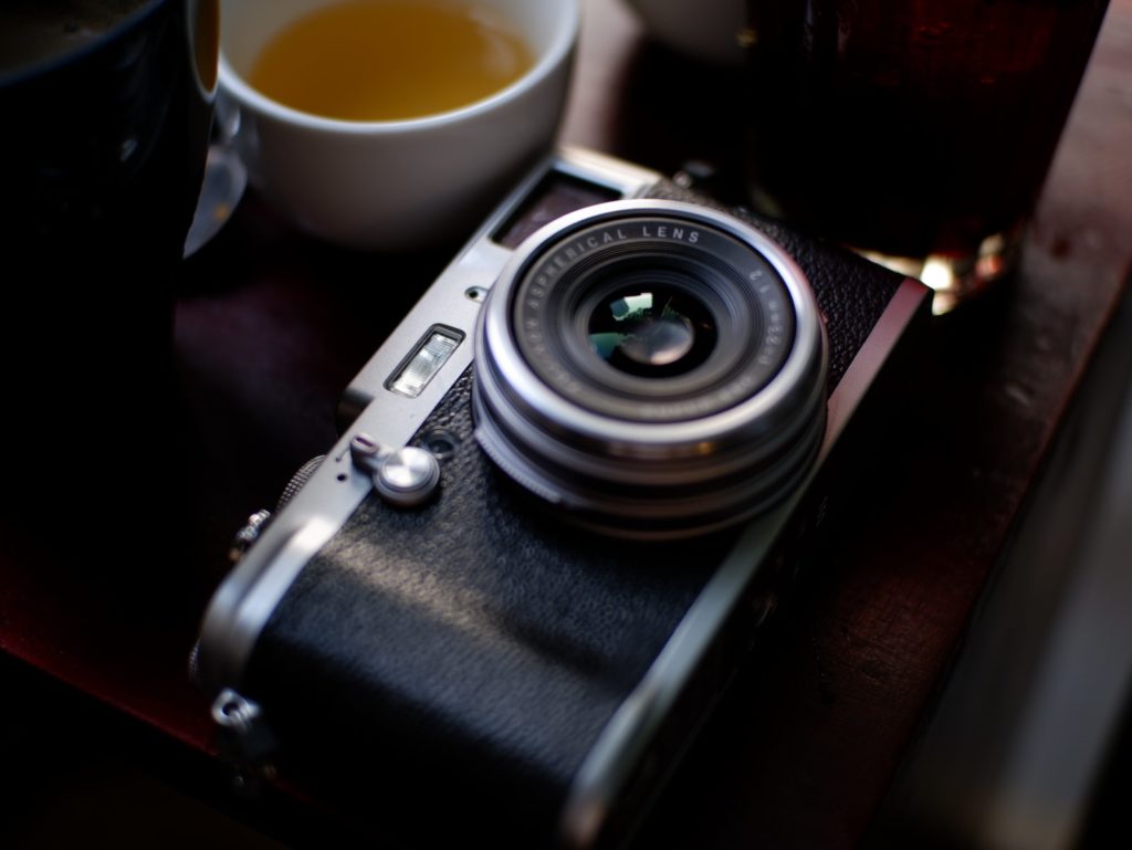 black and silver dslr camera beside white ceramic mug