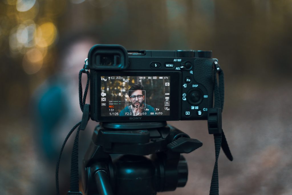 black dslr camera displaying man in blue shirt