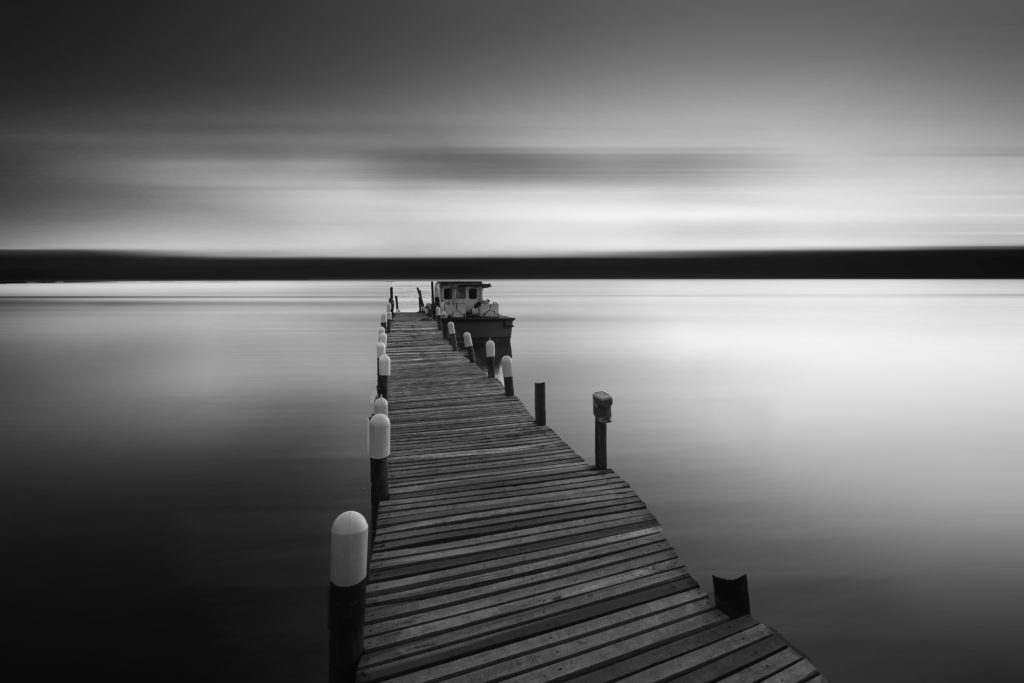 River with jetty and boat in black and white