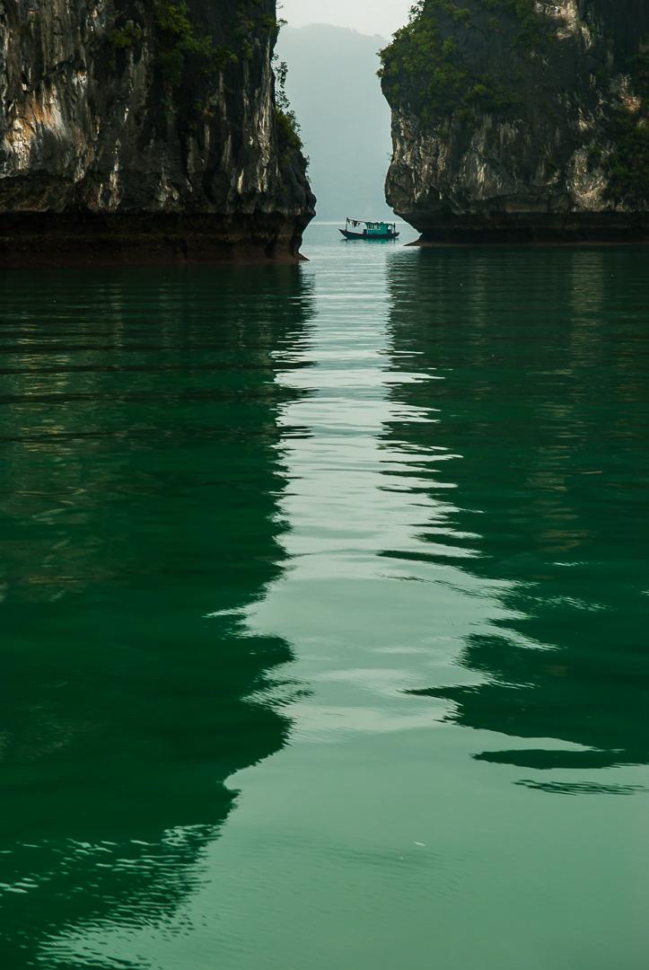 Boat passes between two rocks in Vietnam. Image demonstrates, leading lines and framing compositional rules 