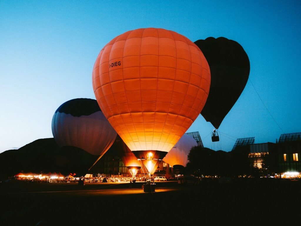 Hot air balloons glowing at twilight against a dark sky.