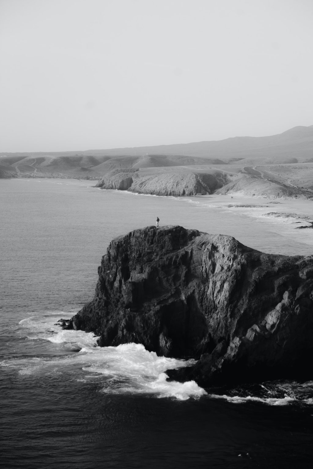 grayscale photo of sea waves crashing on rock formation