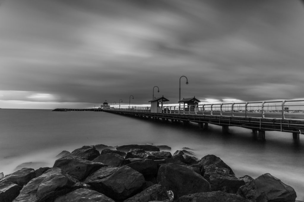 grayscale photo of wooden dock on body of water